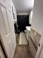 Bathroom with vanity, curtained shower, a textured ceiling, and toilet