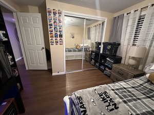 Bedroom featuring a textured ceiling, dark hardwood / wood-style floors, and a closet