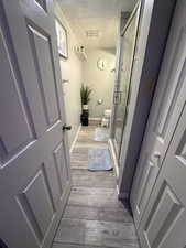 Bathroom featuring toilet, a textured ceiling, hardwood / wood-style flooring, and walk in shower