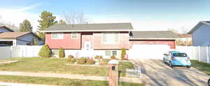 Raised ranch featuring a garage and a front yard