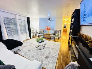 Living room with hardwood / wood-style floors, ceiling fan, and a textured ceiling