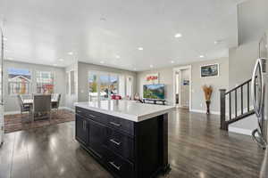 Kitchen featuring dark wood-type flooring, a textured ceiling, and a center island