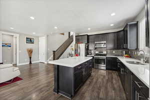 Kitchen with stainless steel appliances, a kitchen island, sink, decorative backsplash, and dark wood-type flooring