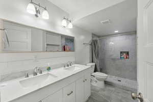 Basement Bathroom with toilet, tile patterned flooring, vanity, and a shower with shower curtain