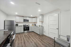 Basement Kitchen with white cabinets, dark hardwood / wood-style floors, sink, and appliances with stainless steel finishes