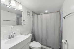 Basement Bathroom with vanity, toilet, a textured ceiling, and tasteful backsplash