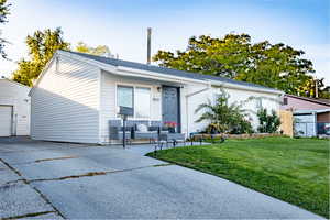 Ranch-style home featuring a front lawn, a garage, and an outdoor structure