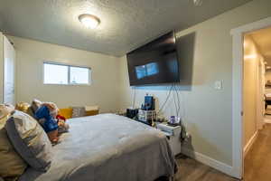 Bedroom with light hardwood / wood-style floors and a textured ceiling