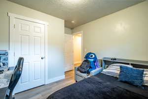 Bedroom with light wood-type flooring and a textured ceiling