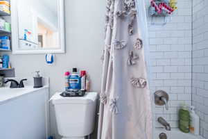 Full bathroom with vanity, shower / bath combo with shower curtain, and toilet