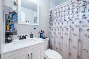 Bathroom with curtained shower, vanity, toilet, and a textured ceiling