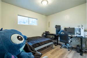 Bedroom with light hardwood / wood-style flooring and a textured ceiling