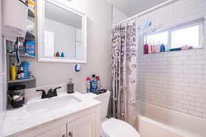 Full bathroom featuring toilet, vanity, shower / bath combo with shower curtain