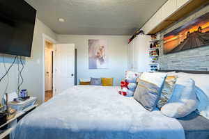 Bedroom featuring hardwood / wood-style flooring and a textured ceiling