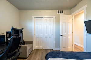 Bedroom featuring hardwood / wood-style floors, a textured ceiling, and a closet