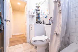 Bathroom featuring a shower with shower curtain, flooring, and toilet