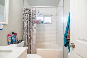 Full bathroom featuring shower / bath combo with shower curtain, vanity, and toilet