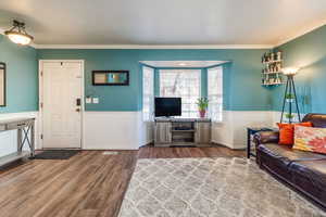 Living room featuring hardwood / wood-style floors, a textured ceiling, and crown molding