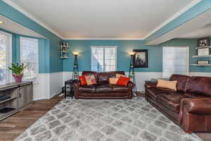 Living room with wood-type flooring, ornamental molding, and a textured ceiling