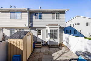 Back of house with a patio and a storage shed