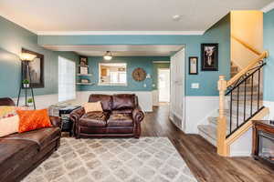 Living room featuring ornamental molding, wood-type flooring, and a textured ceiling