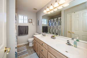 Bathroom featuring toilet, vanity, and a wealth of natural light