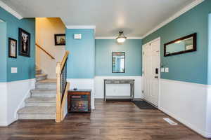 Entrance foyer with dark wood-type flooring, a textured ceiling, and crown molding