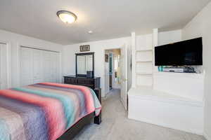 Bedroom with a textured ceiling and light carpet