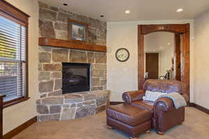 Living room featuring a stone fireplace and light colored carpet