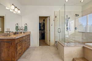 Primary Bathroom featuring walk in shower, vanity, and tile.