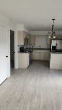 Kitchen featuring light hardwood / wood-style floors, sink, pendant lighting, and appliances with stainless steel finishes