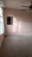 Empty room featuring ceiling fan and carpet floors