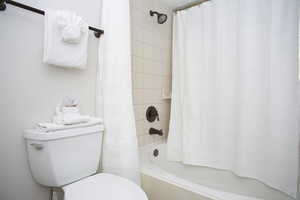 Bathroom with toilet and shower / bathtub combination with curtain