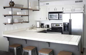 Kitchen with a kitchen breakfast bar, stainless steel appliances, tile countertops, and sink