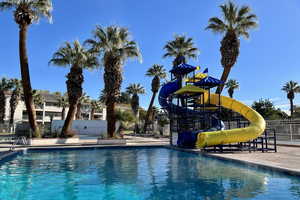 View of swimming pool with a playground and a water slide