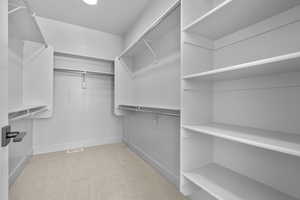 Spacious closet featuring light colored carpet