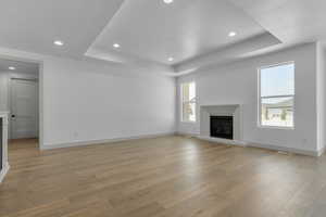 Unfurnished living room with a wealth of natural light, a textured ceiling, and light hardwood / wood-style flooring