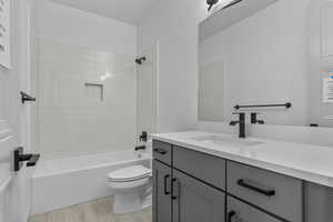 Full bathroom featuring toilet, tiled shower / bath combo, vanity, and hardwood / wood-style floors