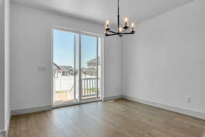 Spare room featuring a chandelier, a textured ceiling, and light hardwood / wood-style floors