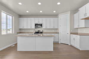 Kitchen with white cabinetry, appliances with stainless steel finishes, sink, and light wood-type flooring