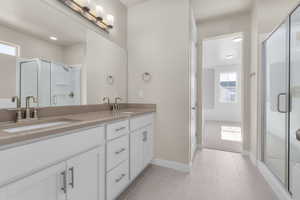 Bathroom featuring walk in shower, vanity, and tile patterned flooring