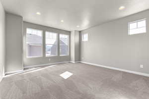 Empty room featuring a textured ceiling and carpet flooring