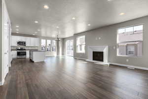 Unfurnished living room with dark hardwood / wood-style flooring, an inviting chandelier, sink, and a textured ceiling