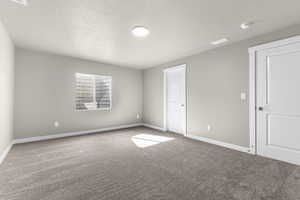 Carpeted spare room with a textured ceiling