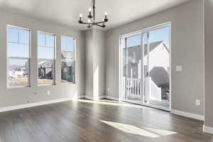 Spare room with a wealth of natural light, a chandelier, and dark hardwood / wood-style flooring