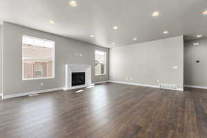 Unfurnished living room with a textured ceiling, dark wood-type flooring, and a healthy amount of sunlight