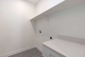 Laundry area featuring hookup for an electric dryer, dark tile patterned flooring, cabinets, and hookup for a washing machine