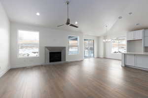 Unfurnished living room with hardwood / wood-style floors, a wealth of natural light, and ceiling fan with notable chandelier