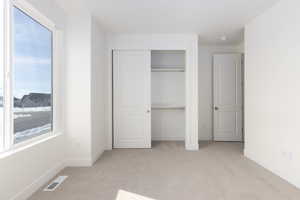 Unfurnished bedroom featuring a closet and light colored carpet