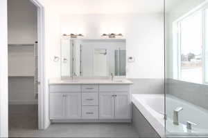 Bathroom featuring vanity, tile patterned floors, and tiled tub